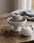     White and gray pumpkin shaped candle jars with lit candles in an elegant neutral autumn displa